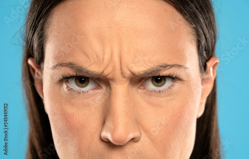 Photo Angry face of a young woman with facial wrinkles closeup