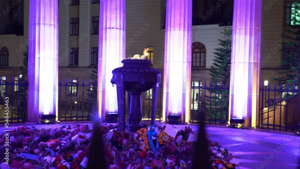 Illuminated Shrine of Remembrance with burning eternal flame, flowers