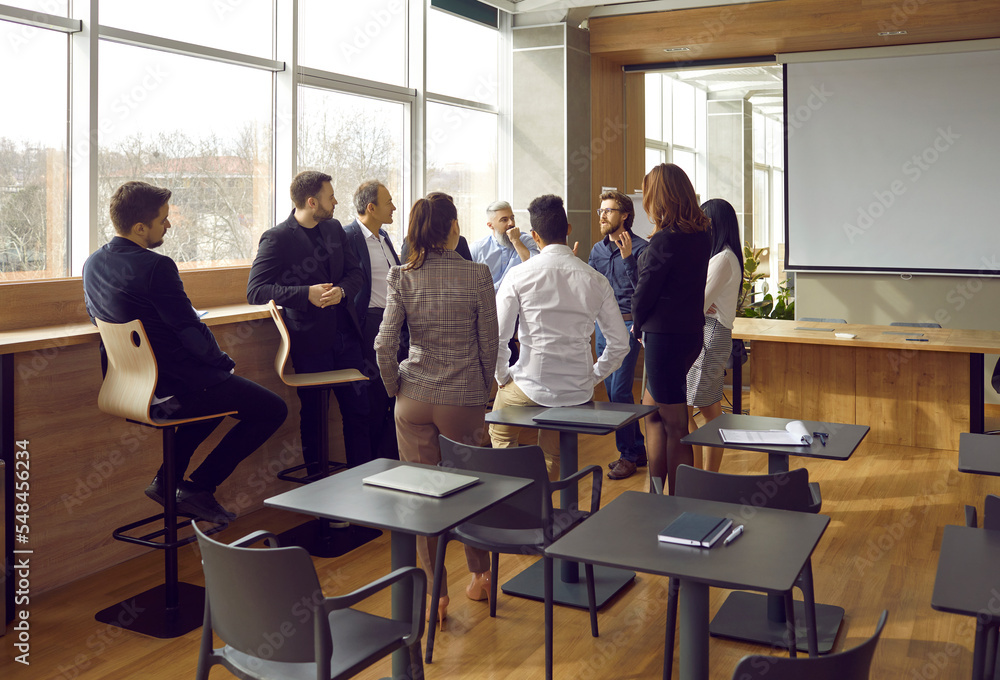 Business coach has casual conversation with group of people after training, lecture or seminar in office. Successful man shares his experience, ideas and life hacks with business people around him. Business coach has casual conversation with group of people after training, lecture or seminar in office. Successful man shares his experience, ideas and life hacks with business people around him.