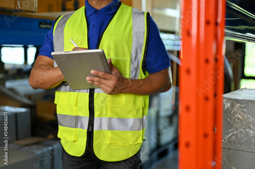 cropped shot, Professional Asian warehouse worker checking inventory list on his tablet