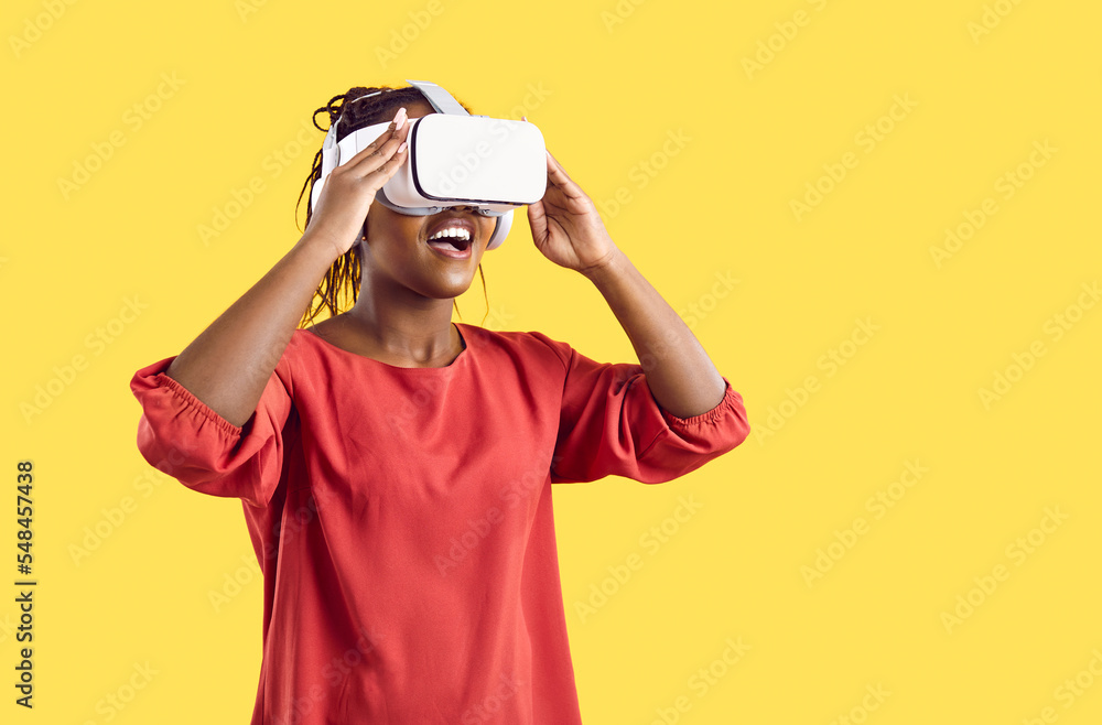 Smiling African American woman enjoy vision in vr glasses isolated on yellow studio background. Happy excited black wear virtual reality headset explore new horizons. Technology concept. Smiling African American woman enjoy vision in vr glasses isolated on yellow studio background. Happy excited black wear virtual reality headset explore new horizons. Technology concept.