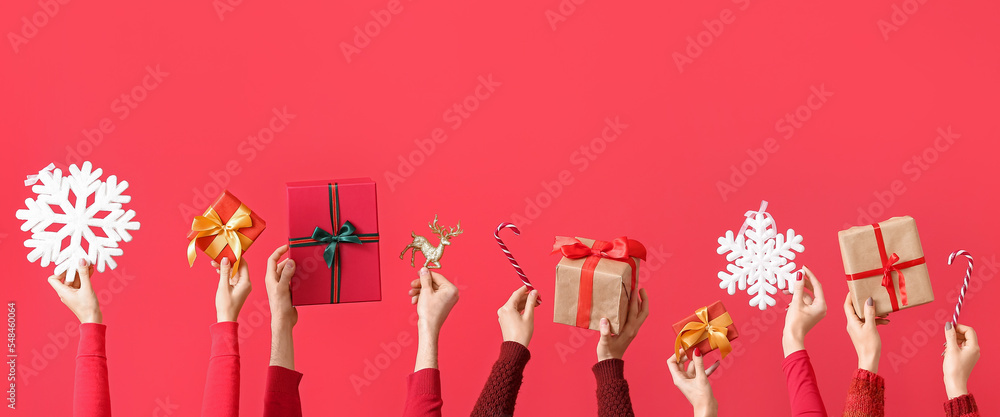 Many hands with Christmas gifts and decorations on red background Many hands with Christmas gifts and decorations on red background