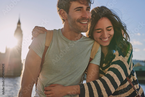 Foto Travel, love and couple hug at big ben for happy holiday, adventure and sunset walk at river