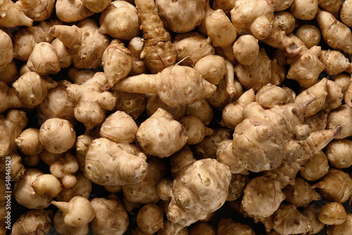 Raw Jerusalem artichoke root, sunchokes as background. View from above.