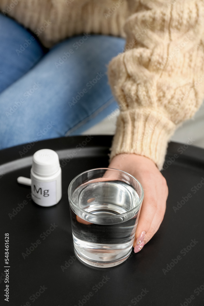 Woman with glass of water and pills at table, closeup Woman with glass of water and pills at table, closeup