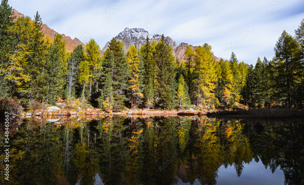 Fototapeta premium A lake and the mountains in the Swiss alps, during an autumn day near the village of Poschiavo, Switzerland - October 2022.