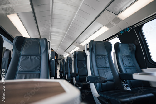 Passenger is standing amidst empty seats. Interior of modern illuminated subway or intercity train. Concept of rail transportation.