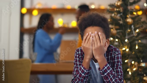 Sad, desperate little boy closing eyes during parents quarrel on christmas eve photo
