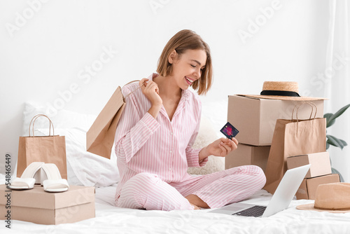 Pretty woman with credit card and shopping bag in bedroom