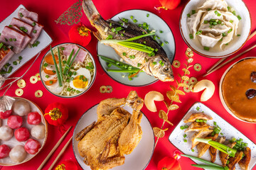 Traditional Chinese lunar New Year dinner table, party invitation, menu background with pork, fried fish, chicken, rice balls, dumplings, fortune cookie, nian gao cake, noodles, chinese decorations
