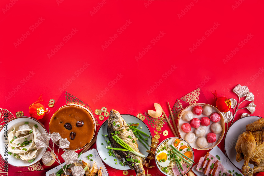 Traditional Chinese lunar New Year dinner table, party invitation, menu background with pork, fried fish, chicken, rice balls, dumplings, fortune cookie, nian gao cake, noodles, chinese decorations Traditional Chinese lunar New Year dinner table, party invitation, menu background with pork, fried fish, chicken, rice balls, dumplings, fortune cookie, nian gao cake, noodles, chinese decorations