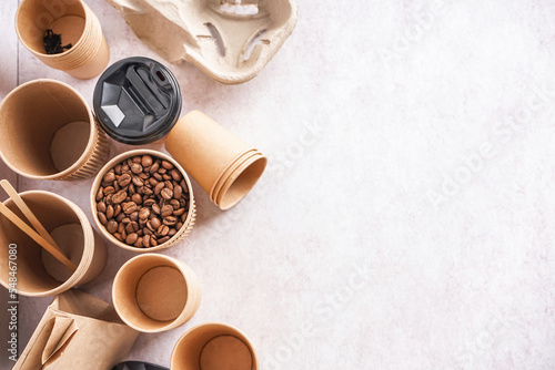 Different paper cups and coffee beans on light background