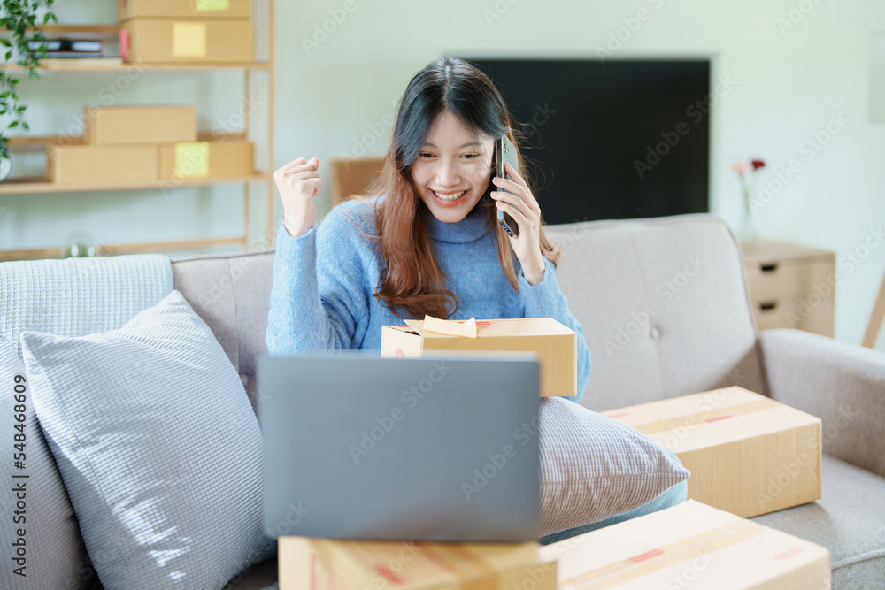 Starting small business entrepreneur of independent Asian woman smiling using computer laptop with cheerful success of online marketing package box items and SME delivery concept Starting small business entrepreneur of independent Asian woman smiling using computer laptop with cheerful success of online marketing package box items and SME delivery concept