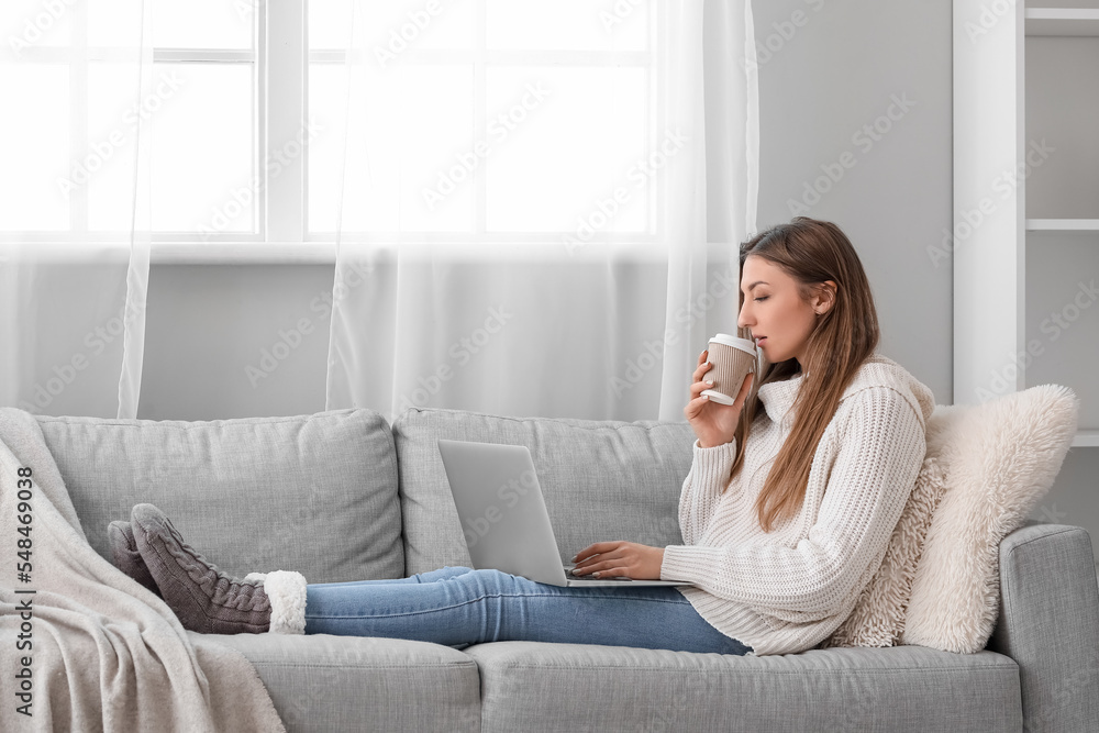 Young woman with cup of coffee using laptop at home Young woman with cup of coffee using laptop at home