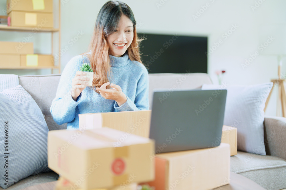 Starting small business entrepreneur of independent Asian woman smiling using computer laptop with cheerful success of online marketing package box items and SME delivery concept Starting small business entrepreneur of independent Asian woman smiling using computer laptop with cheerful success of online marketing package box items and SME delivery concept