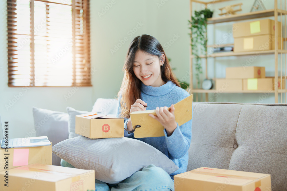Starting small business entrepreneur of independent Asian woman smiling using computer laptop with cheerful success of online marketing package box items and SME delivery concept Starting small business entrepreneur of independent Asian woman smiling using computer laptop with cheerful success of online marketing package box items and SME delivery concept