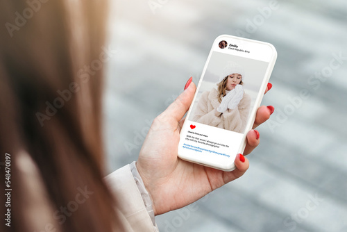 Woman looking at beautiful model's photo on mobile phone