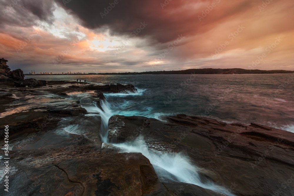 Obraz premium Waves surge up though a deep narrow chasm in rocks near Sydney