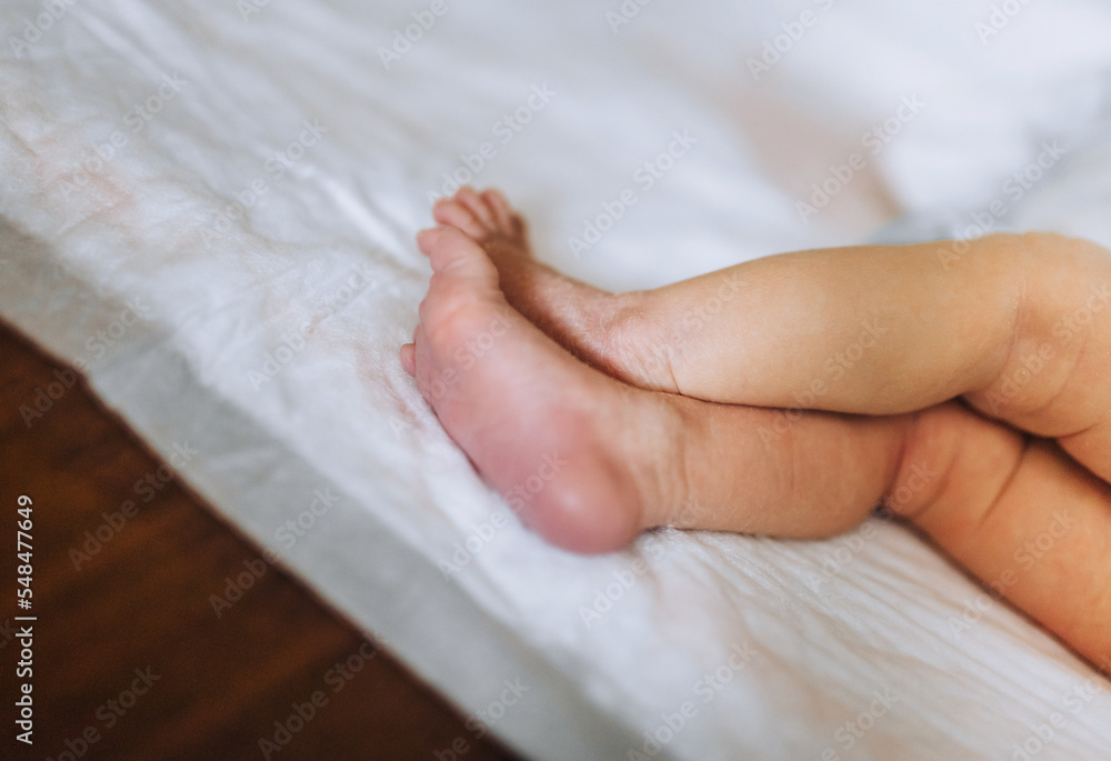 Small legs, feet of a newborn baby sleeping on the bed. Small legs, feet of a newborn baby sleeping on the bed.