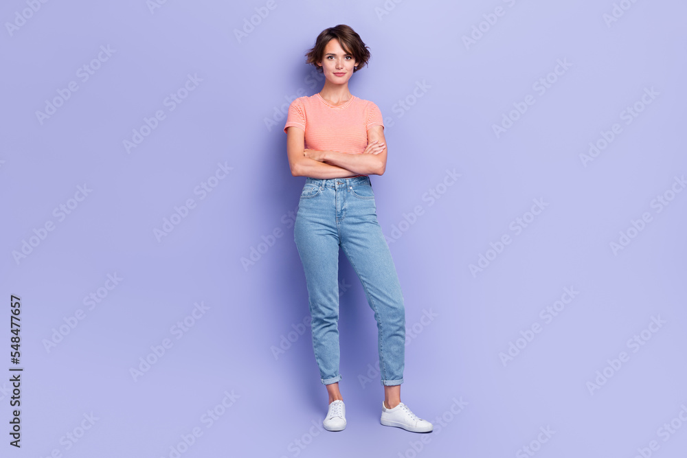 Full length photo of shiny confident girl dressed orange t-shirt hands crossed smiling isolated purple color background Full length photo of shiny confident girl dressed orange t-shirt hands crossed smiling isolated purple color background