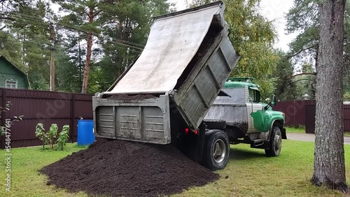 The dump truck unload soil to the ground. Dump truck unloading process.
 photo