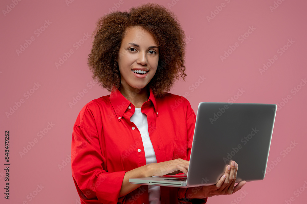 Pretty curly-haired woman in red jacket working on laptop Pretty curly-haired woman in red jacket working on laptop