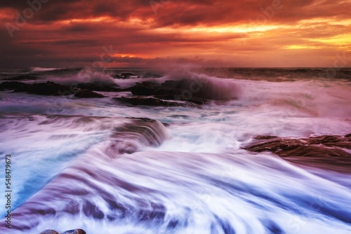 Large waves wash into the tidal ocean pool at sunrise