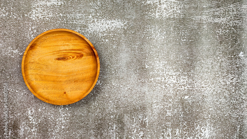Empty round wooden plate on grunge textured background