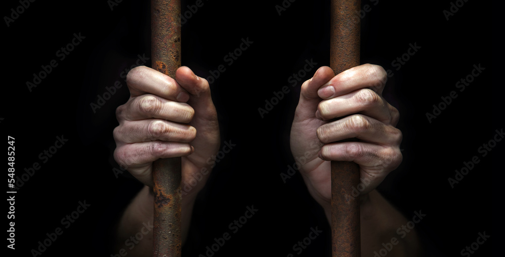 The prisoner's hands are holding on to the iron bars The prisoner's hands are holding on to the iron bars