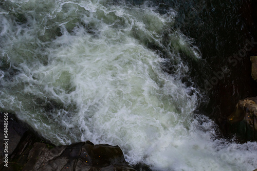 rapids of mountain rivers with fast water and large rocky boulders. Rapid flow of a mountain river in spring, close-up