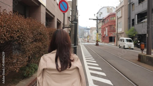 Asian woman walks the street by street railway. Nagasaki Japan. Back shot. No face.