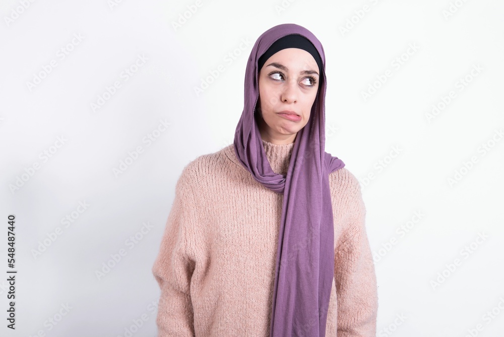 beautiful muslim woman wearing hijab and warm jumper over white background making grimace and crazy face, screaming out of control, funny lunatic expressing freedom and wild. beautiful muslim woman wearing hijab and warm jumper over white background making grimace and crazy face, screaming out of control, funny lunatic expressing freedom and wild.