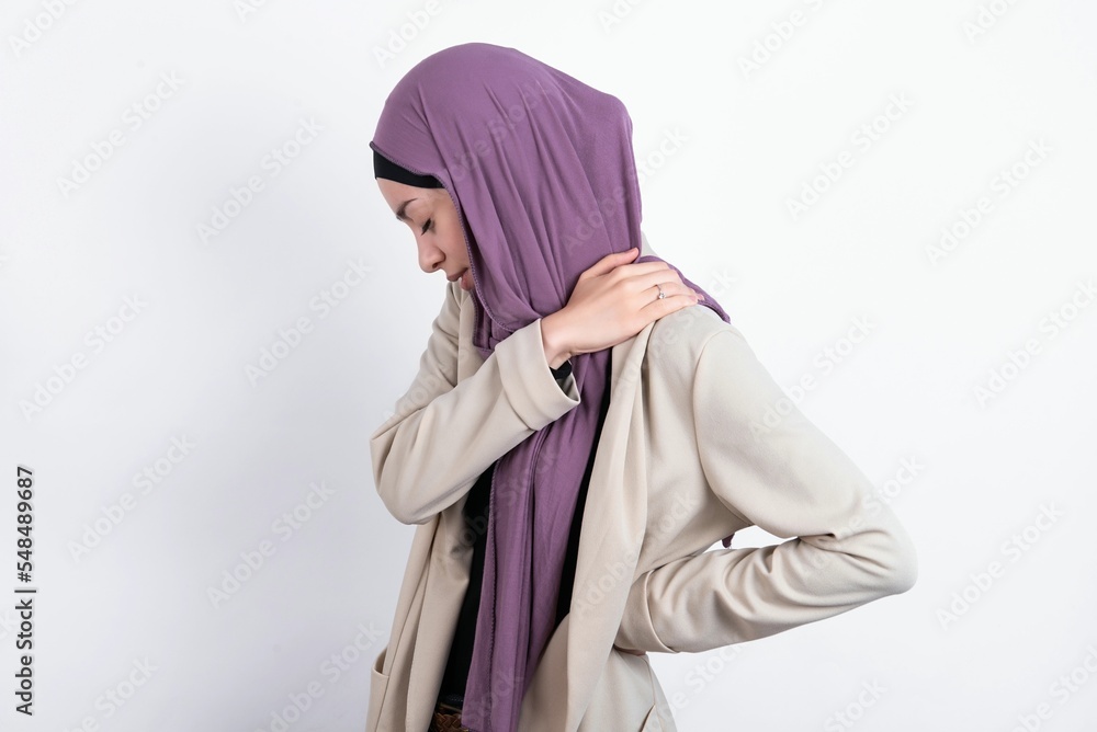 young beautiful muslim woman wearing hijab and jacket over white background got back pain young beautiful muslim woman wearing hijab and jacket over white background got back pain