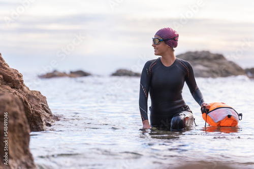 Obraz na plátně Woman swimming in open water with wetsuit and buoy