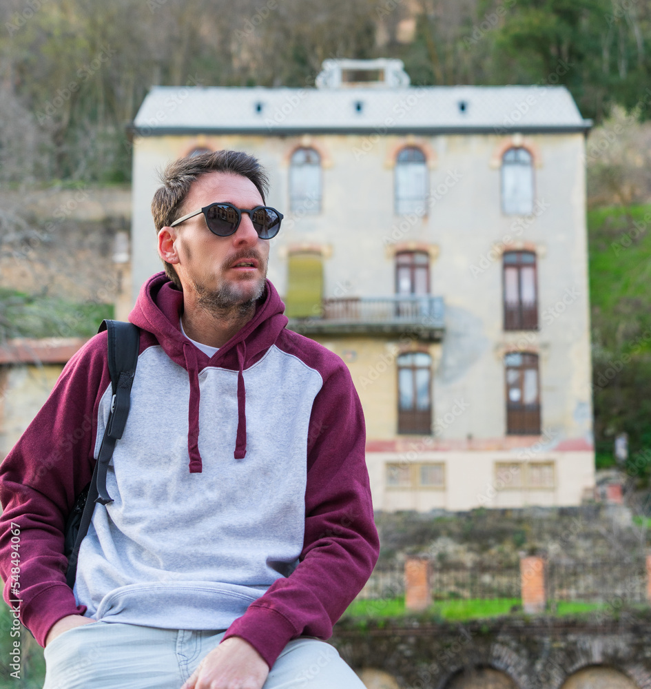 Person with a serious face, and a two-colored sweatshirt, with glasses, seated. Person with a serious face, and a two-colored sweatshirt, with glasses, seated.