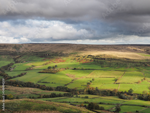View across the Rosedale valley to the remote Rosedale Ironstone Railway and ruins of the kilns of the East Rosedale Mines picked out by the sunlight, North York Moors National Park, UK photo