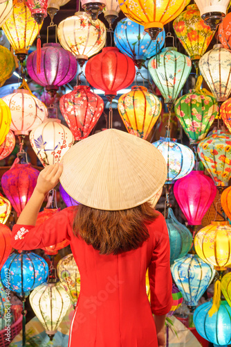 happy woman wearing Ao Dai Vietnamese dress with colorful lanterns  traveler sightseeing at Hoi An ancient town in central Vietnam.landmark for tourist attractions.Vietnam and Southeast travel concept