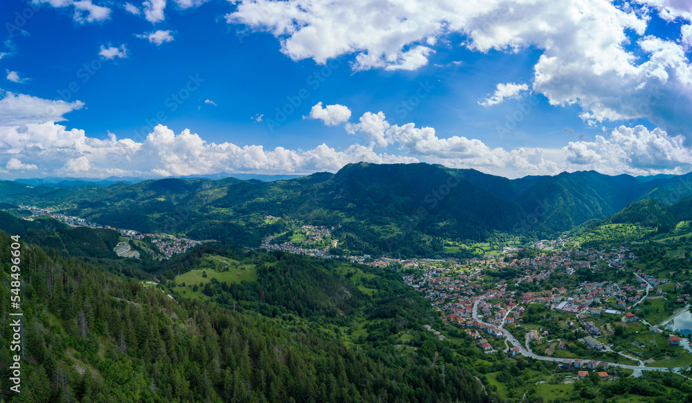 Fototapeta premium Bulgarian town Smolyan with lake, vegetation and clouds. Rhodope Mountains. Panorama, top view