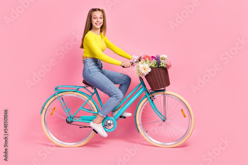 Full length photo of cute adorable schoolgirl wear yellow crop top driving bike isolated pink color background © deagreez