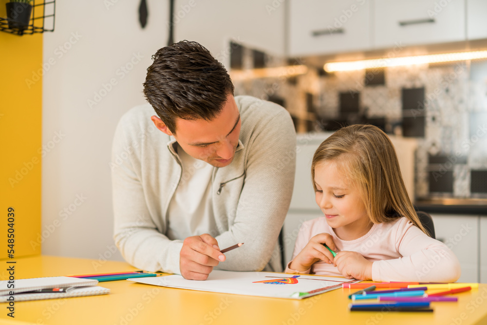 Little girl and her father enjoy drawing together at their home. Little girl and her father enjoy drawing together at their home.