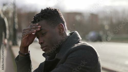 Worried black man suffering alone in emotional pain outside in city sidewalk street2