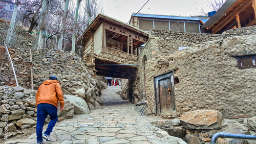 Walking in the streets of Karimabad, Hunza Valley, Pakistan, with traditional buildings built of cobblestone and wood seen along the way. photo