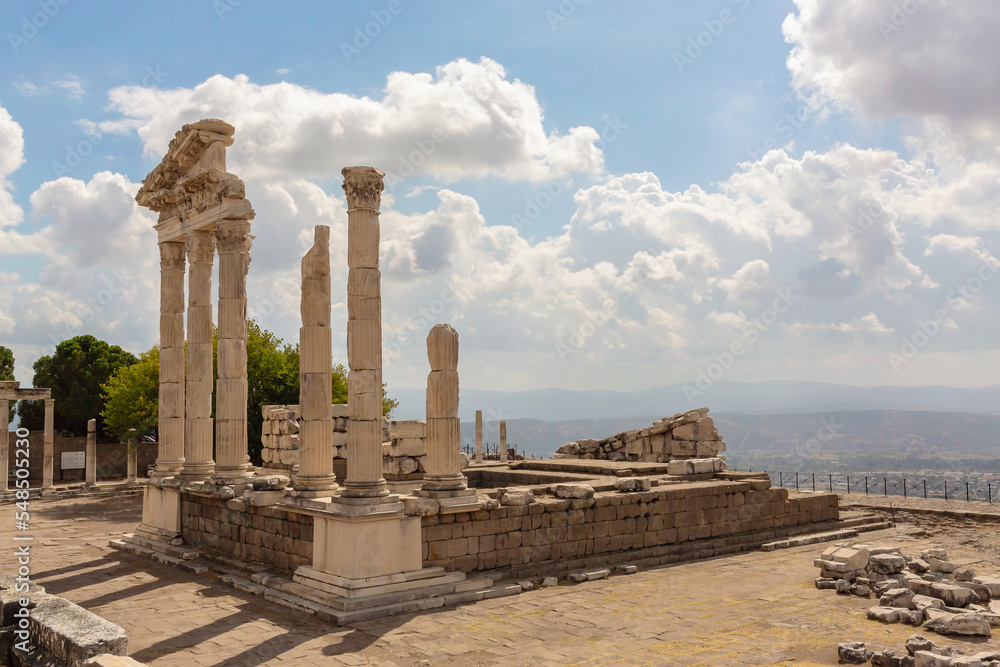 The ruined Temple of Trajan in Pergamon Ancient City. Corinthian order stone-cut relief on the frieze. Dramatic sky at background. History, art or architecture concept. Bergama, Turkey