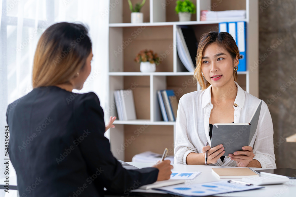 Two young Asian businessmen talk and discuss financial information. and the details planned by happily jotting down notes in a book... Two young Asian businessmen talk and discuss financial information. and the details planned by happily jotting down notes in a book...