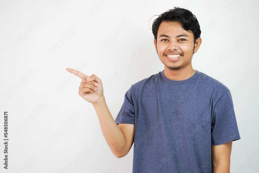 Smiling or happy handsome young Asian man with his finger pointing isolated on white background with copy space Smiling or happy handsome young Asian man with his finger pointing isolated on white background with copy space
