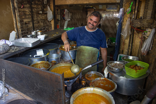 A cook and an owner of a local roadside restaurant or a  dhaba, cooking food during lunch hour photo