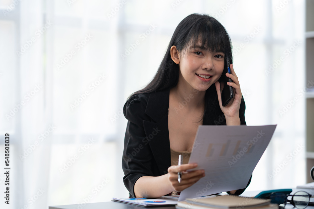 Asian businesswoman in formal suit in office happy and cheerful during using smartphone and working Asian businesswoman in formal suit in office happy and cheerful during using smartphone and working
