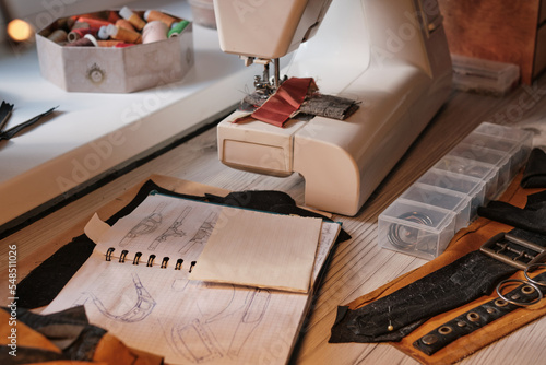 Close-up of work corner with sewing machine, notepad with sketches.