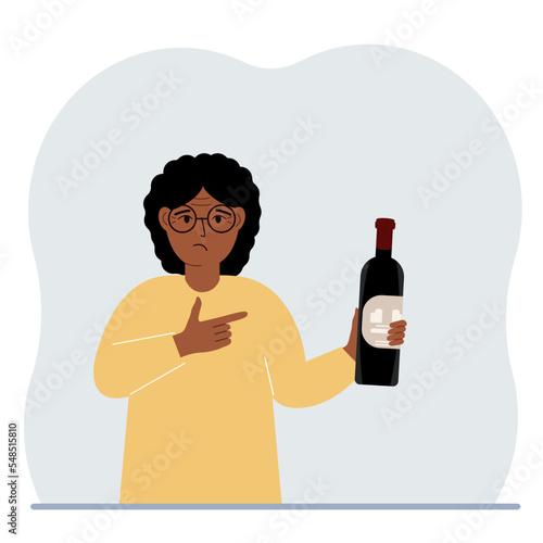A woman holds a bottle of alcohol or wine in his hand. Sad woman suffering from severe alcohol addiction. Alcoholism abuse concept.
