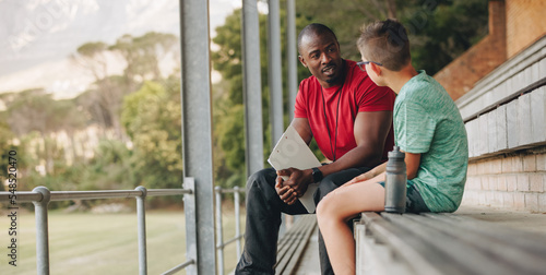 School coach talking a young student while sitting outside